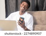 Small photo of overexcited handsome businessman seated using laptop and mobile phone