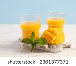 
Mango juice in a glass. tropical juice. Lemonade. Mint leaves. Blue background. Summer drink.