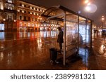 Small photo of Bus stop. Nevsky Prospekt, St. Petersburg, Russia - November 10, 2010. People wait at the bus stop in the evening during the rain. Waiting for public transport. Rainy autumn weather.