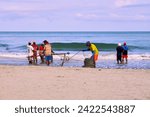 Small photo of Cartagena, Bolivar Colombia - 1 February 2024: The fishermen finish winding the ropes with which they drag the trammel net with the fish collected on the beaches of Cartagena de Indias, Colombia.