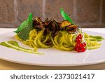 Spaghetti alla Nerano with courgette cream, provolone del monaco and fried courgettes served in an elegant restaurant