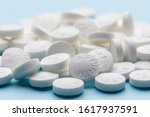 White aspirin pills on blue paper background. Pile of aspirin. Medical background