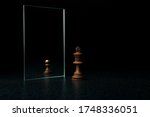 Small photo of the king is reflected in the mirror as a pawn on black background. underestimation of their abilities