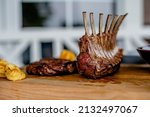 Small photo of Grilling meat. Medium rare grilled premium dry-aged rib-eye steak and lamb chops cut on wooden board. Barbeque kamado grill. Prime beef and lamb grilling. Rib-eye steak and lamb chops sliced onboard