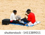 Small photo of 06.08.2008. Margete, Kent, UK. A black couple enjoying a picnic on the beach Marget kent