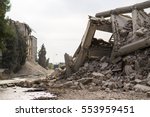 Industrial concrete building destructed by earthquake strike. Disaster scene full of debris, dust and crashed buildings.