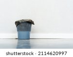 Plastic trash bin with a plastic bag on a gray wall background. copy space