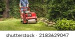 Small photo of Man using gas powered aerating machine to aerate residential grass yard. Groundskeeper using turf aeration equipment for lawn maintenance.