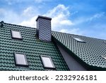 Roof with green roof tiles , the chimney is covered with gray slate shingles