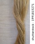Small photo of Fibers of natural uncolored flax or hemp on the flax canvas background. Growing demand for natural fibers. Copy space. Vertical image.