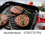 Beef burger patties sizzling on a hot barbecue pan. White background. Top view