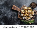 Cooked Clams vongole in a pan. Black background. Top view. Copy space.