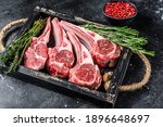 Raw lamb meat chops steaks in a wooden tray. Black background. Top view.
