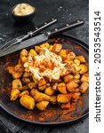 Small photo of Patatas Bravas, traditional Spanish tapas, baked potato with spicy tomato sauce. Black background. Top view