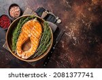Roasted Salmon Trout Fish Steak in a vintage wooden plate with thyme and rosemary. Dark background. Top view. Copy space
