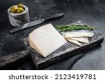 Dutch goat cheese sliced on a wooden cutting board. Black background. Top view