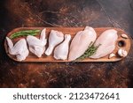 Raw chicken meat, assortment of parts - drumstick, breast fillet, wings, thigh with spices. Dark background. Top view