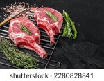 Small photo of Fresh Raw Tomahawk rib eye beef steaks on grill. Black background. Top view. Copy space.
