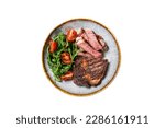 Small photo of BBQ Grilled rib eye steak, fried rib-eye beef meat on a plate with green salad. Isolated on white background