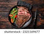 Small photo of Barbecue grilled and sliced wagyu Rib Eye beef meat steak on a plate. Dark background. Top view.