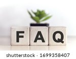 FAQ concept on wooden cubes and flower in a pot in the background