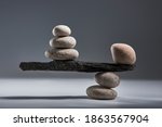 Balancing pyramid of sea pebbles on a gray background, the concept of harmony and balance, heavy and light. Stones in the form of scales with balancing stones.