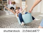 Small photo of A cheerful little girl is dragged around the bathroom in a laundry bowl. Child is happy cheerful lifts up rece fun home entertainment during chores.