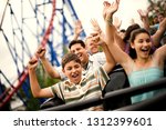 Smiling family riding on a rollercoaster at an amusement park.