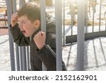 Small photo of Cute athletic little boy child 6-7 year old playing in playground. Amusement park for kids. Outdoor activities and games for children. Aggressive, angry, crazy boy growls