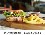 Small photo of Club sandwhich with french fries and tomato sauce served on a wooden plunk in a restaurant. Close up, depth of field