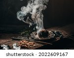 Charcoal burning with incense, incense resin, rosemary, 
laurel, lavender on a rustic wooden table,smudging, energetic cleansing .Sahumar
