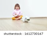 Small photo of Infatuated cute little girl playing plastic toy lizard robot with a remote control. The nano-toy chameleon, modern technology of toys. Electronic pet.