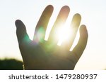 Small photo of Hand of a young person catching the sun, icon of overcoming the limits. Get what is inalienable. Hot colors, pursue your dreams.