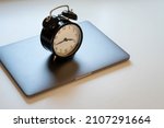 Small photo of Alarm clock standing on laptop. Concept of work hours, deadline and limit screen time.