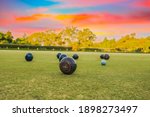 Lawn bowls balls in a field after the game with a colourful sunset