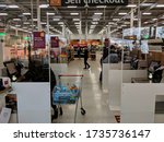 Small photo of MANSFIELD, UK - MAY 18, 2020: Self service checkouts separated into cubicles by perspex screens to prevent infection spread, with people bagging and paying for their groceries during COVID-19 pandemic