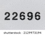 Small photo of Black Number 22696 on the white wall. Spray paint.two hundred and two thousand six hundred ninety-sixtwo hundred and two thousand six hundred ninety-six