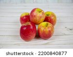 Small photo of Bright pink apples of the Crips Pink variety (Latin Malus domestica) stacked in a pile on a gray wooden table. Vegetables and fruits. Useful products.