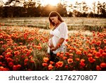 A pregnant model posing for a photoshoot in a field 