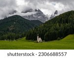 Beautiful Church of St John of Nepomuk (Chiesetta di San Giovanni) in Ranui with a dramatic sky, Val di Funes, Dolomites, Italy