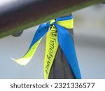 A closeup of a blue and yellow ribbon tied to a metal pole in support of Ukraine
