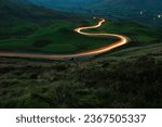 Small photo of A long exposure photograph of a winding road with car light trails