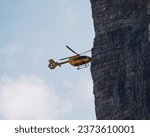 Small photo of TRENTINO, IT - May 17, 2021: An aerial view of a helicopter flying above a rocky cliff, providing an expansive perspective of the landscape in Italy, Trentino