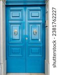 Small photo of This stock photo features a stunning blue double door entrance to a brick building, adorned with elegant and decorative knockers