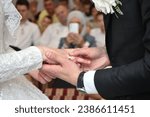 Small photo of A closeup shot of the groom putting a ringer on the bride's finger during the ceremony
