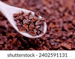 Small photo of A close-up of organic raw cacao nibs in a spoon on a table