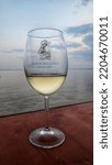 Small photo of Pomorie, Bulgaria - August 19 2022: the ninetieth anniversary of the founding of the first Black Sea Gold wine cellar; a glass of white wine against the backdrop of the Black Sea at sunset