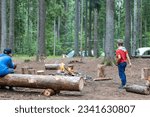 Small photo of Two young boy scouts have built fire and watching the flame. The guys have fun and relax in the scout camp in the fresh air among the forest. Scouting hiking camping Tourism Active lifestyle.