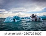 Big pieces of ice (floe) from glacier in the lake, ice islands, mountains and dark sky, Jökulsárlón - Glacier Lagoon, Southeast Iceland
