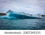 Big piece of ice (floe) from glacier in the lake, ice islands, mountains and cloudy sky, Jökulsárlón - Glacier Lagoon, Southeast Iceland